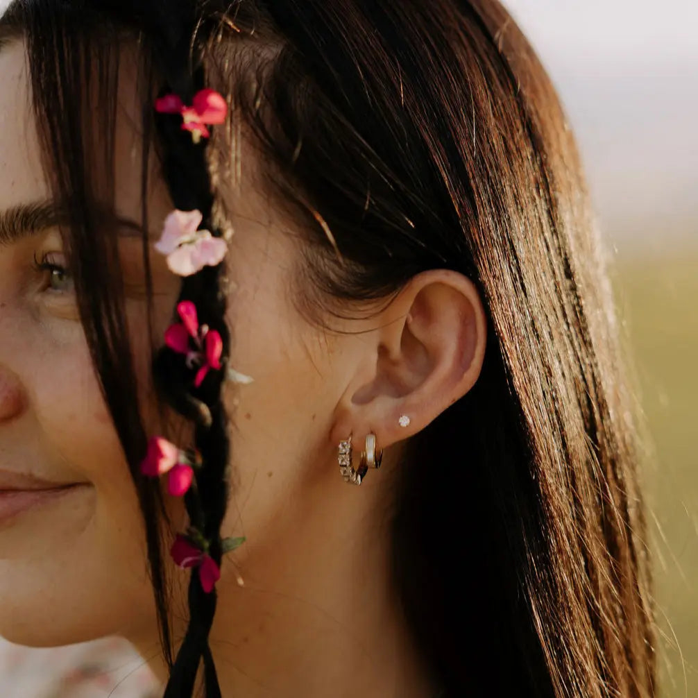 Close-up of a woman's ear with floral hair and earrings.