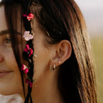 Close-up of a woman's ear with floral hair and earrings.