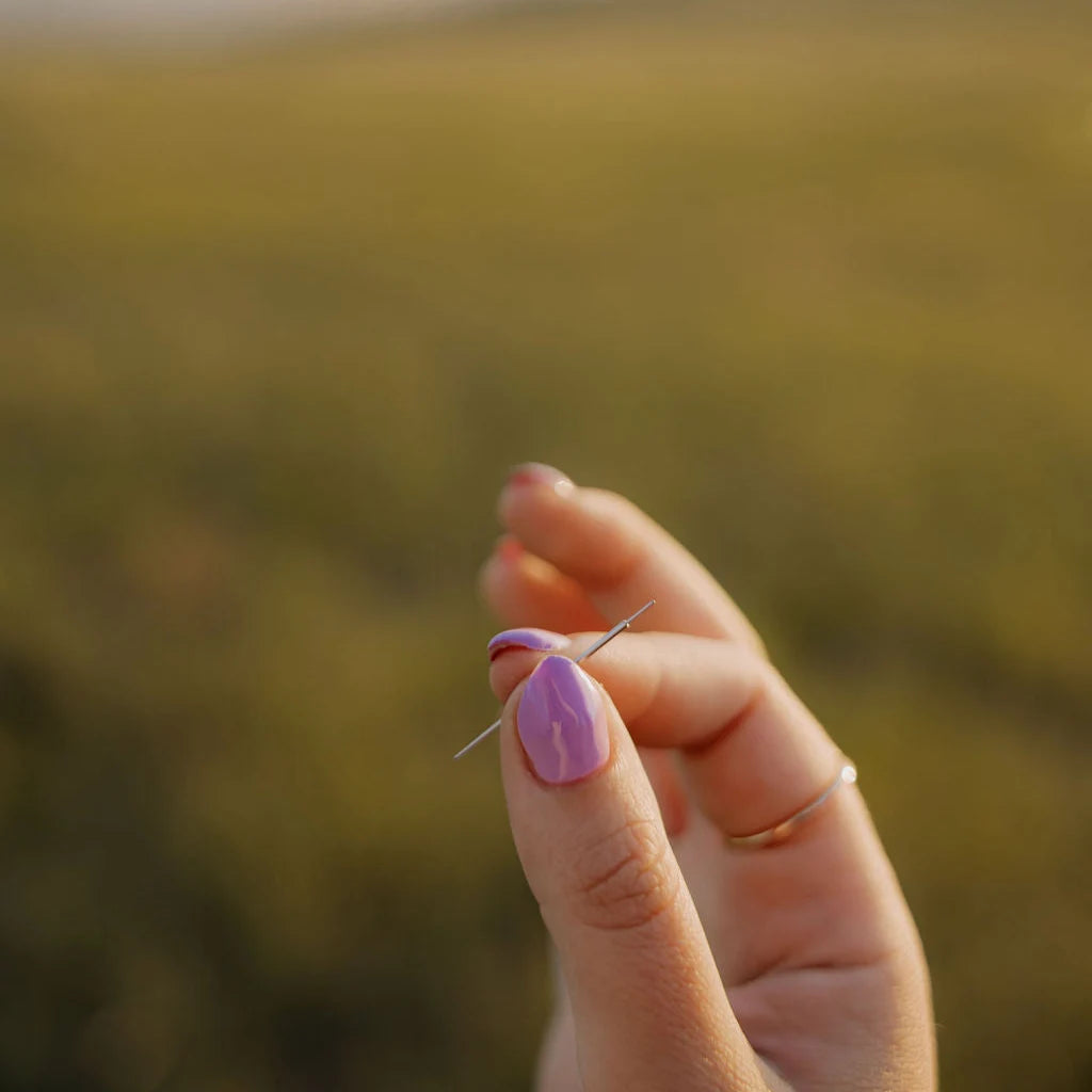 Hand holding a flat back applicator with a blurred natural background