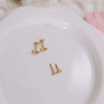 Gold earrings on a white dish with a soft, blurred background