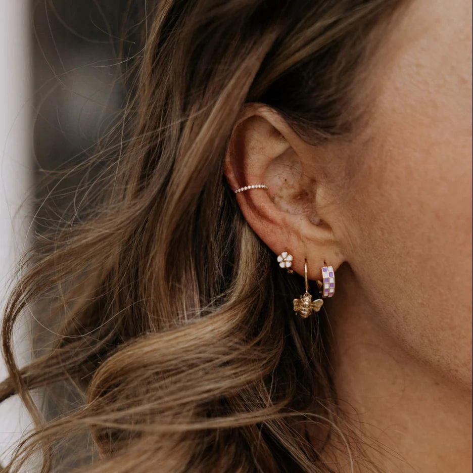 Close-up of an ear with multiple earrings and brown hair. 