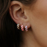 Close-up of an ear wearing colorful checkered hoop earrings.