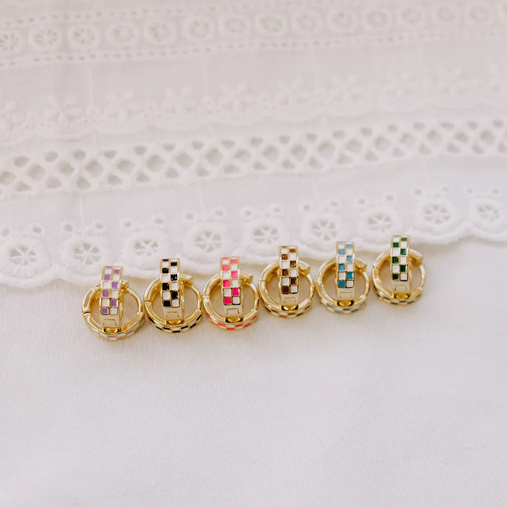 Set of gold hoop earrings with colorful checkered centers on a white lace background