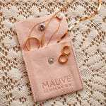 Load image into Gallery viewer, Gold earrings in a pink 'MAUVE JEWELRY CO.' pouch on a textured beige background
