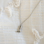 Load image into Gallery viewer, Silver necklace with a boot pendant on a textured white background
