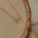 Load image into Gallery viewer, Gold necklace with a small diamond pendant on a wooden surface

