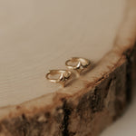 Gold earrings on a wooden surface