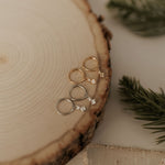 Load image into Gallery viewer, Gold earrings on a wooden surface with greenery
