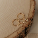 Load image into Gallery viewer, Gold hoop earrings with a small diamond on a wooden surface
