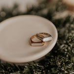 Two gold rings on a white dish with a blurred background