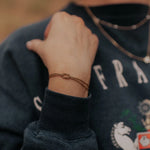 Close-up of a person wearing a dark blue sweater with visible branding, focusing on a bracelet on their wrist.