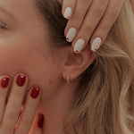 Load image into Gallery viewer, Close-up of a person with red nail polish touching their face, wearing a floral top.
