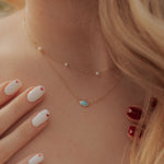 Close-up of a person wearing a delicate turquoise necklace with a blurred background