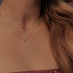 Load image into Gallery viewer, Close-up of a necklace with a turquoise pendant on a person with long hair.
