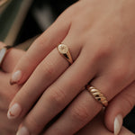 Close-up of a hand wearing two gold rings with a blurred background