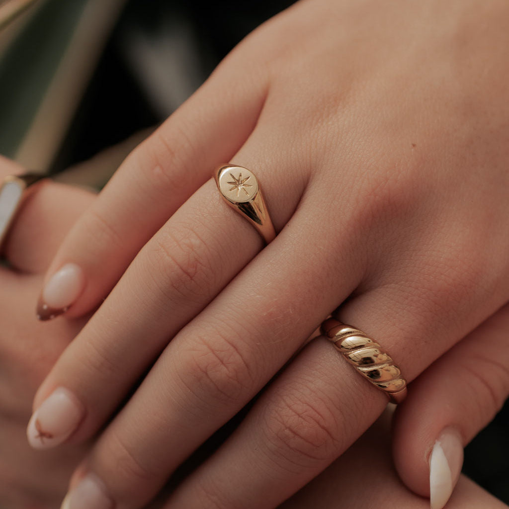 Close-up of a hand wearing two gold rings with a blurred background