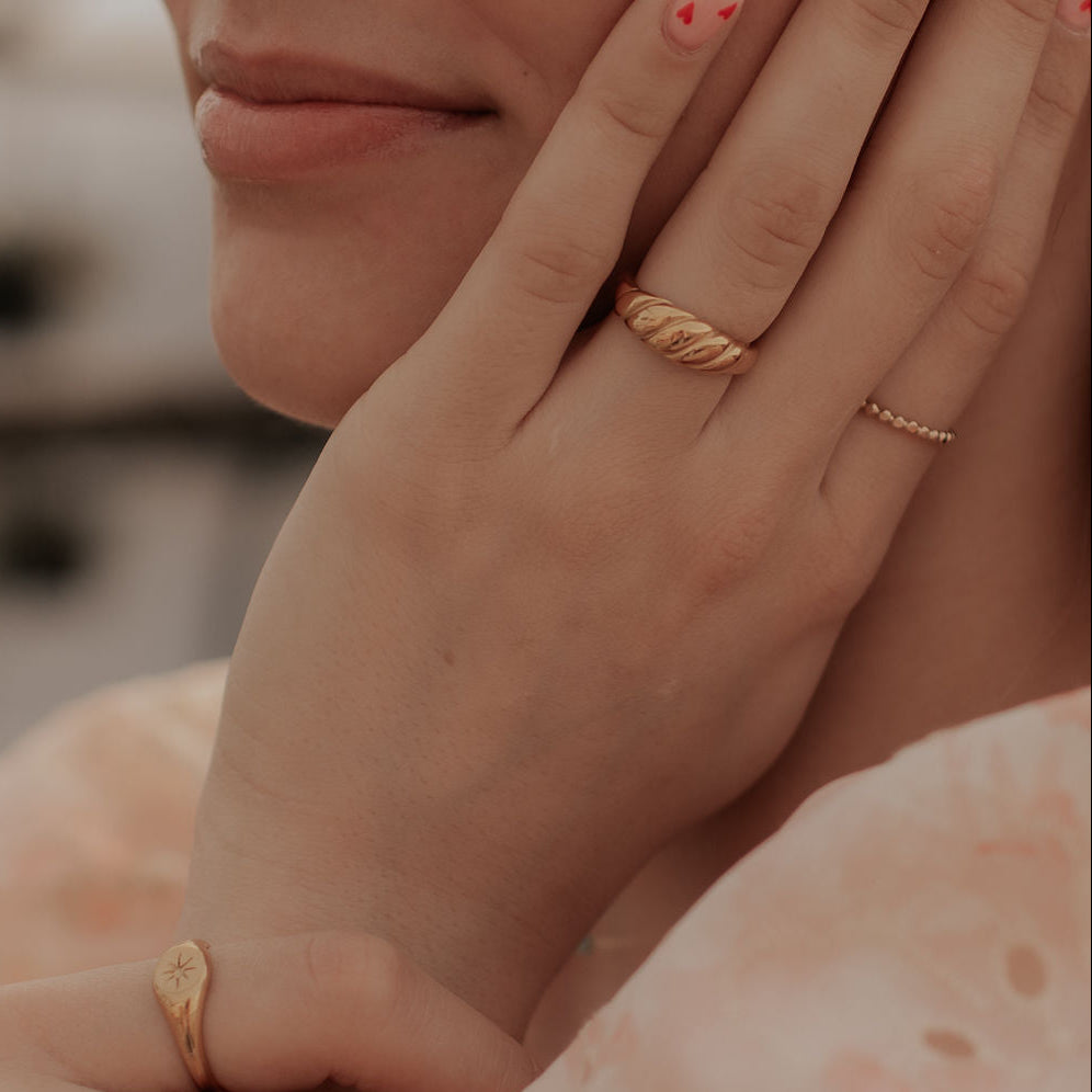 Close-up of a person's hands with gold rings on a blurred background