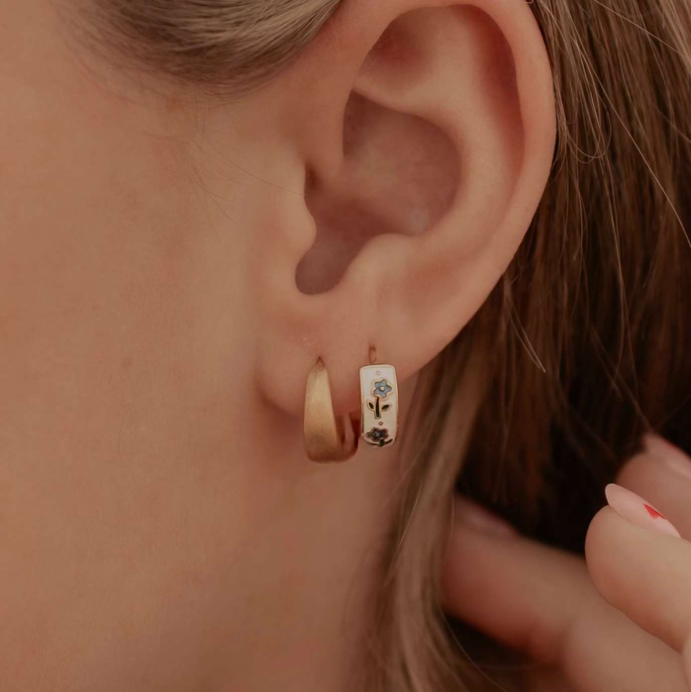 Close-up of an ear wearing a small hoop earring with a decorative center.