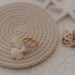 Ring with pearl details on a rope mat with starfish and shell decorations.