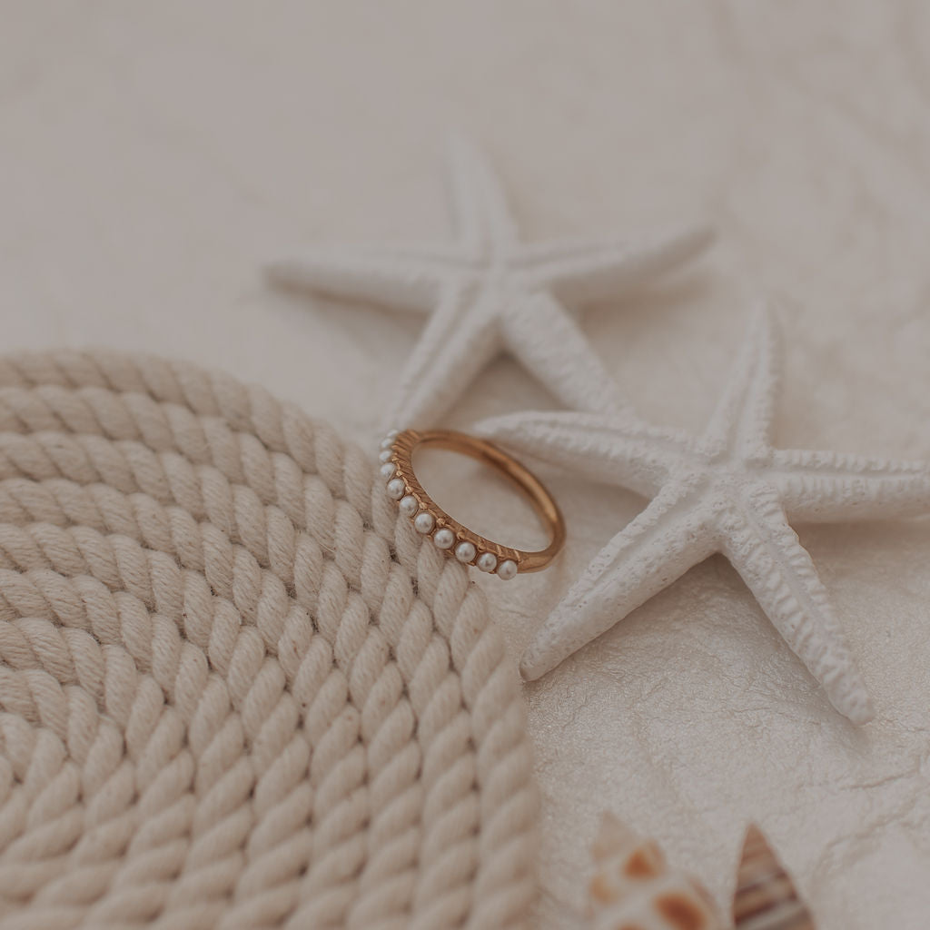 Gold ring on a textured surface with starfish and a shell