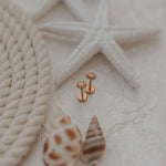 Load image into Gallery viewer, Gold sunshine earrings on a textured beige surface with starfish and rope.
