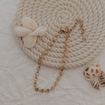 Gold bracelet with seashells on a textured beige surface