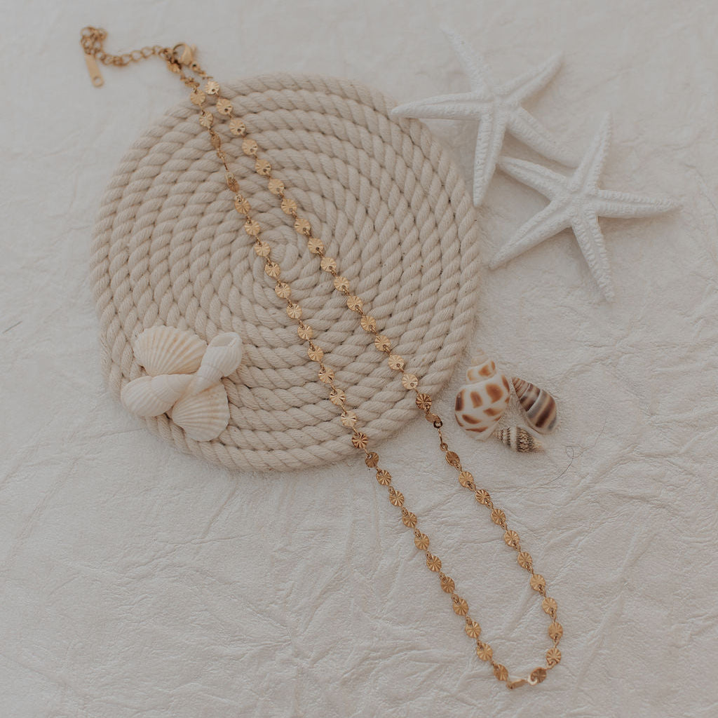 Nautical-themed with rope handle, starfish, and shells on a textured beige background with gold necklace