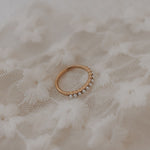 Gold ring with small pearls on a textured beige fabric background