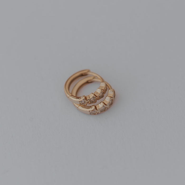 Gold star earrings with a small stone on a gray background