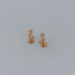 Pair of gold star earrings on a light gray background