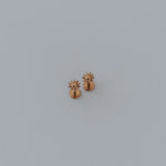 Small gold sun earring on a light gray background