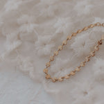 Gold bracelet on a textured white fabric background