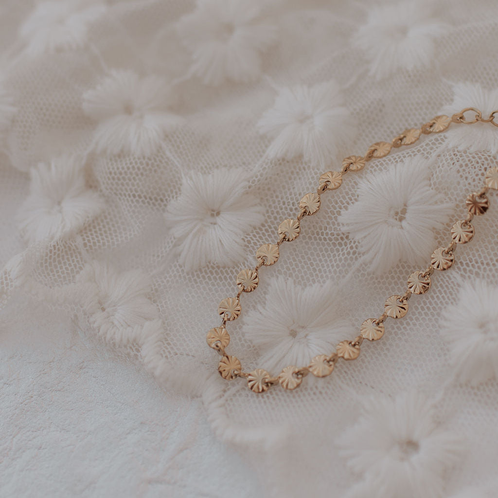 Gold bracelet on a textured white fabric background
