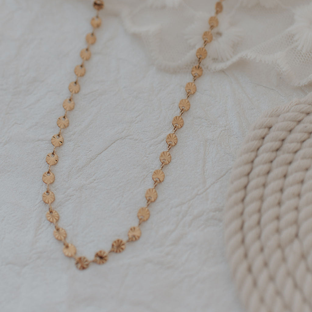 Gold necklace on a textured white surface