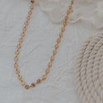 Load image into Gallery viewer, Gold necklace on a textured white surface
