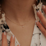 Gold necklace with a teardrop pendant worn by a person