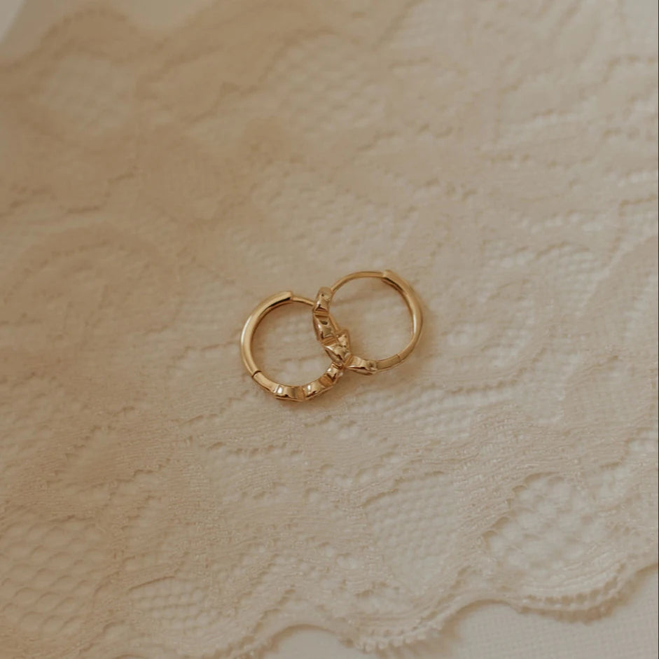 Gold hoop earrings on a textured beige surface