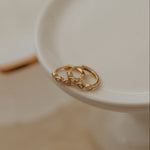 Two gold rings on a white dish with a blurred background