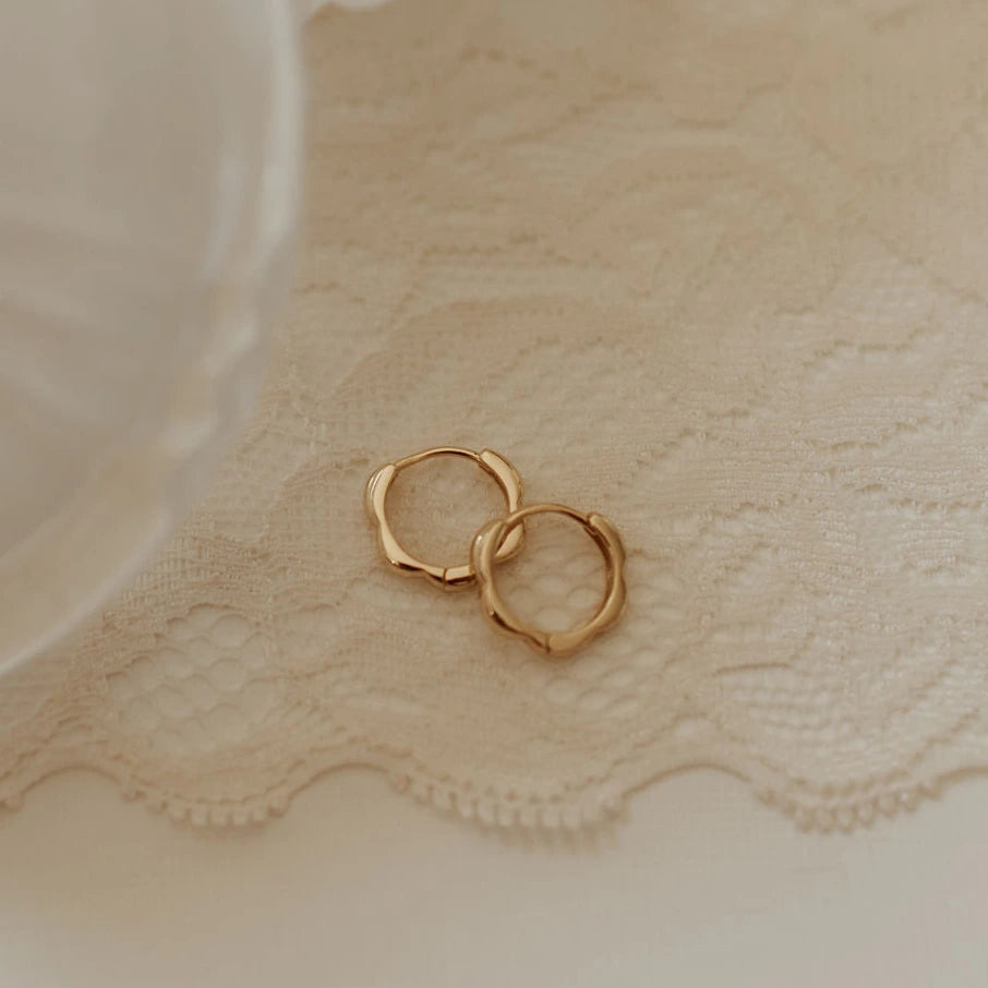 Gold hoop earrings on a textured beige fabric background