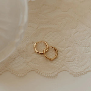 Gold hoop earrings on a textured beige fabric background
