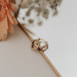 Load image into Gallery viewer, Gold diamond earrings with intricate design on a white surface with flowers in the background
