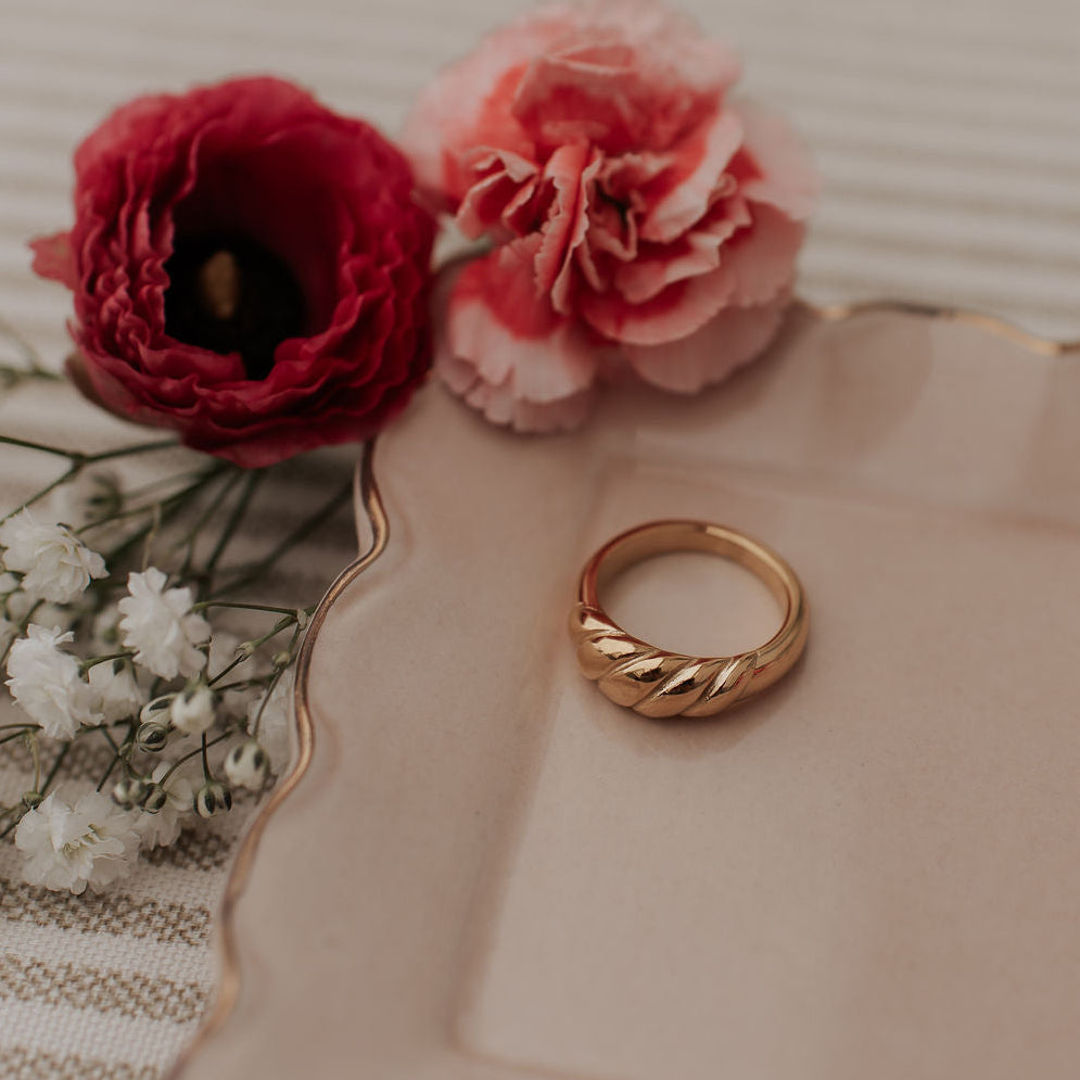 Gold ring on a decorative plate with red and pink flowers