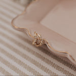 Load image into Gallery viewer, Gold earrings on a pink plate with flowers in the background
