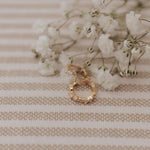 Load image into Gallery viewer, Gold earrings on a textured beige surface with small white flowers
