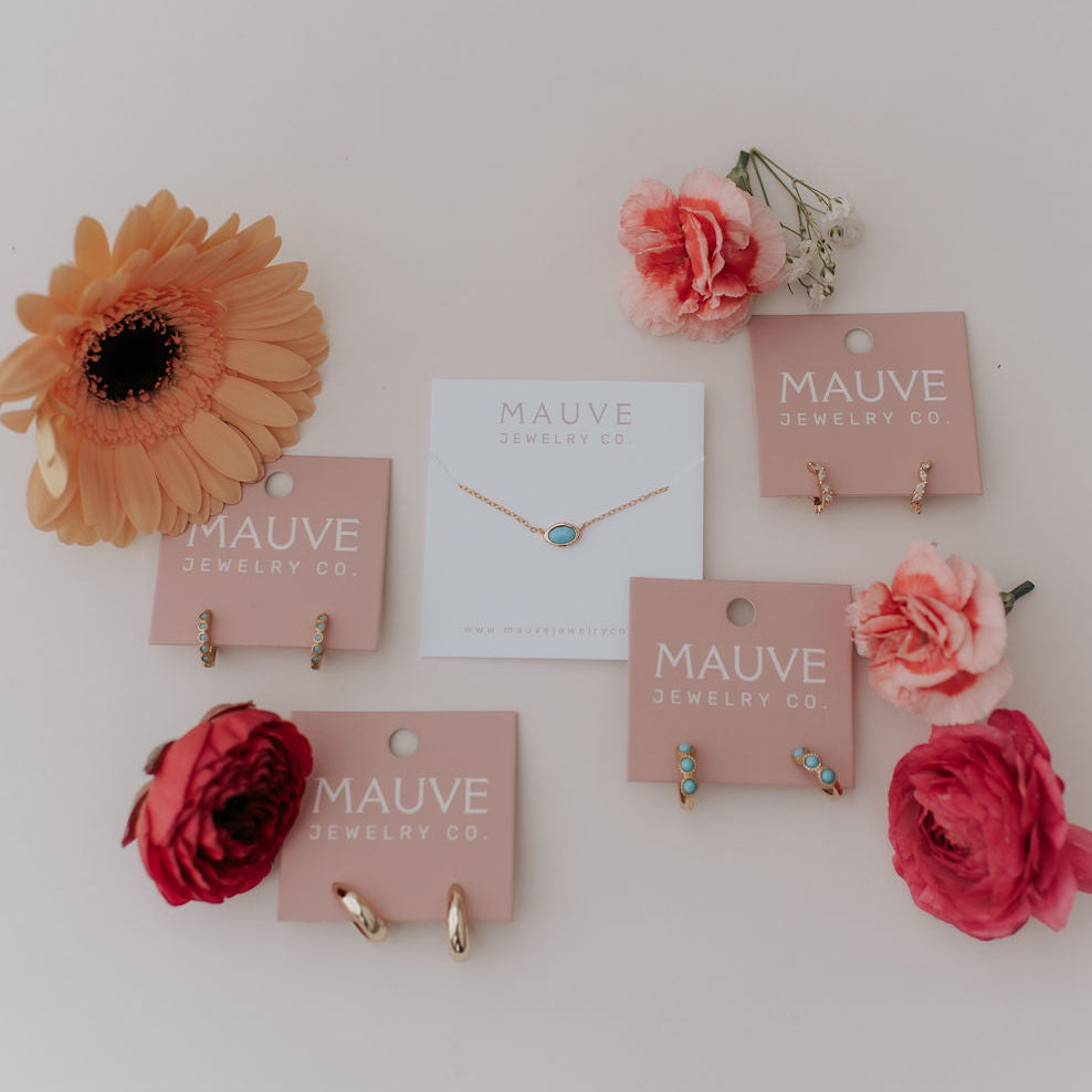 Jewelry display with necklaces on pink cards against a white background