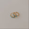 Two gold earrings with turquoise stones on a light gray background