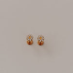 Pair of gold daisy flat back earrings on a light gray background