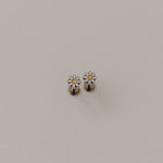 Small silver daisy flat back earrings with a floral design on a light gray background