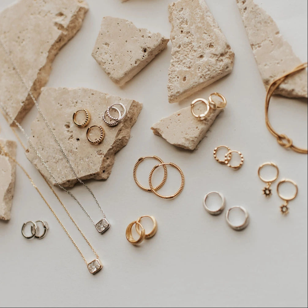 Gold jewelry including rings and necklaces on a textured surface