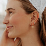 Close-up of a woman wearing gold earrings with a blurred background